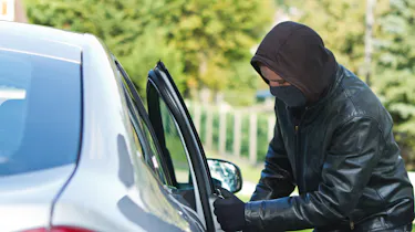Man wearing a hoodie stealing a car
