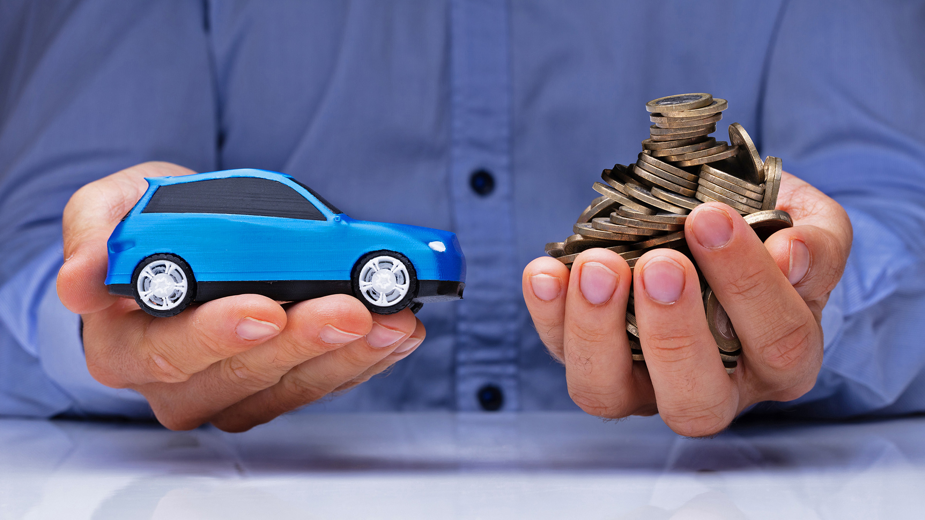 Hands holding toy car and pile of coins