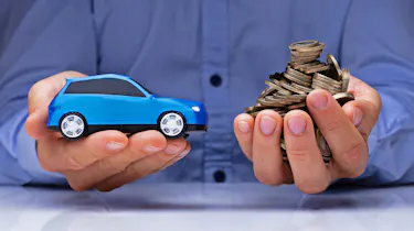 Hands holding toy car and pile of coins